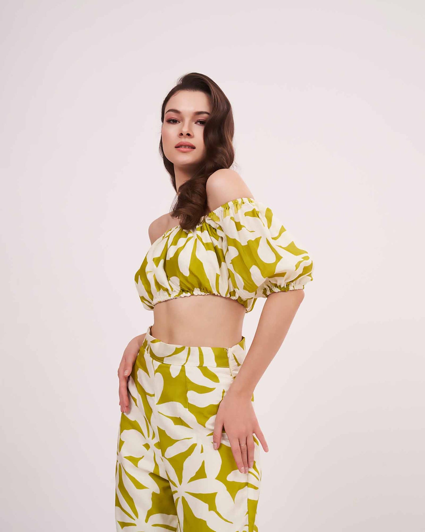 Side-angled standing view with slight head tilt, showing pant slit and the relaxed drape of the wide-legged green co-ord trousers.