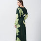 Back view of the model in green floral satin dress, showing the tie-back detail and flowy silhouette from behind.