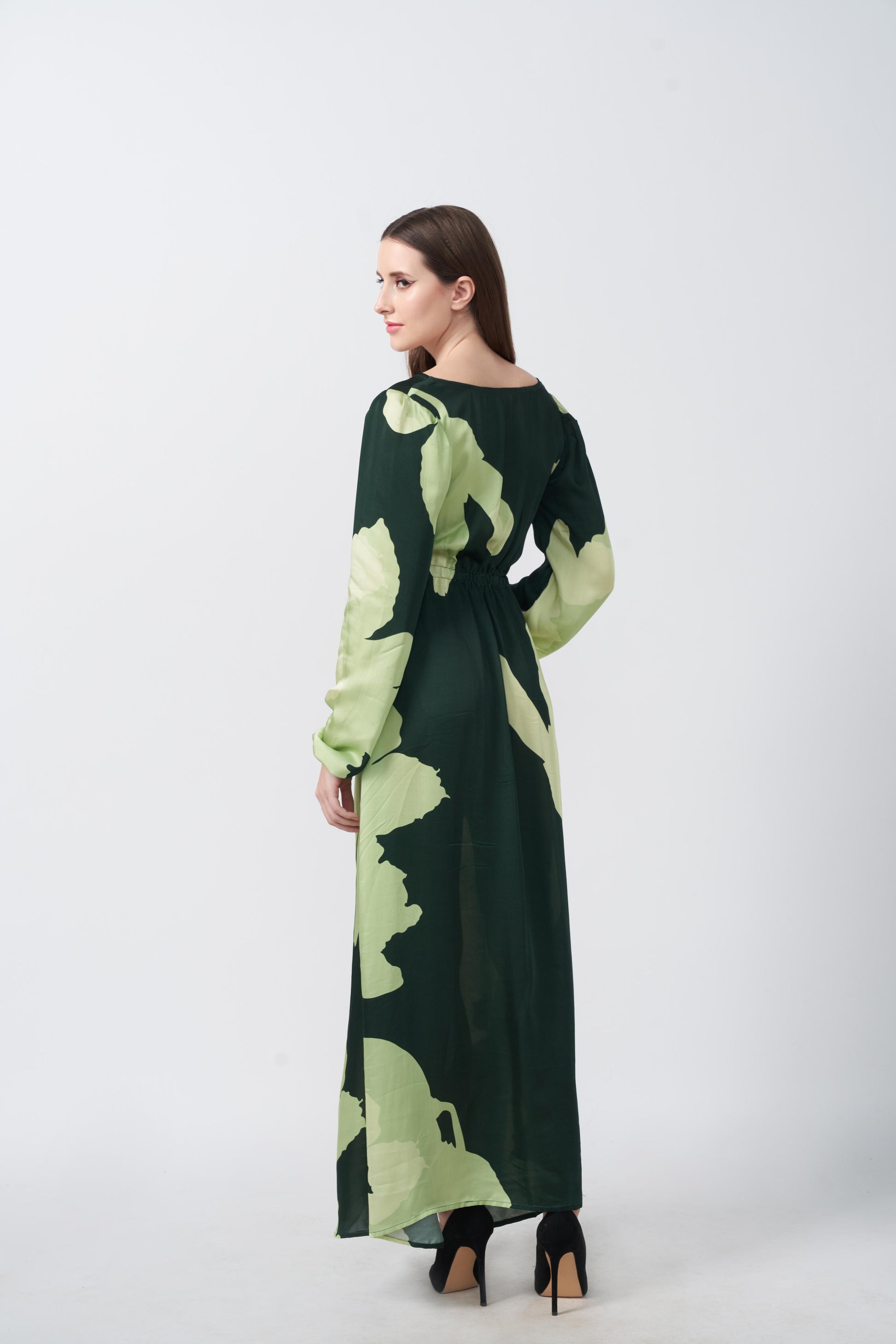 Back view of the model in green floral satin dress, showing the tie-back detail and flowy silhouette from behind.