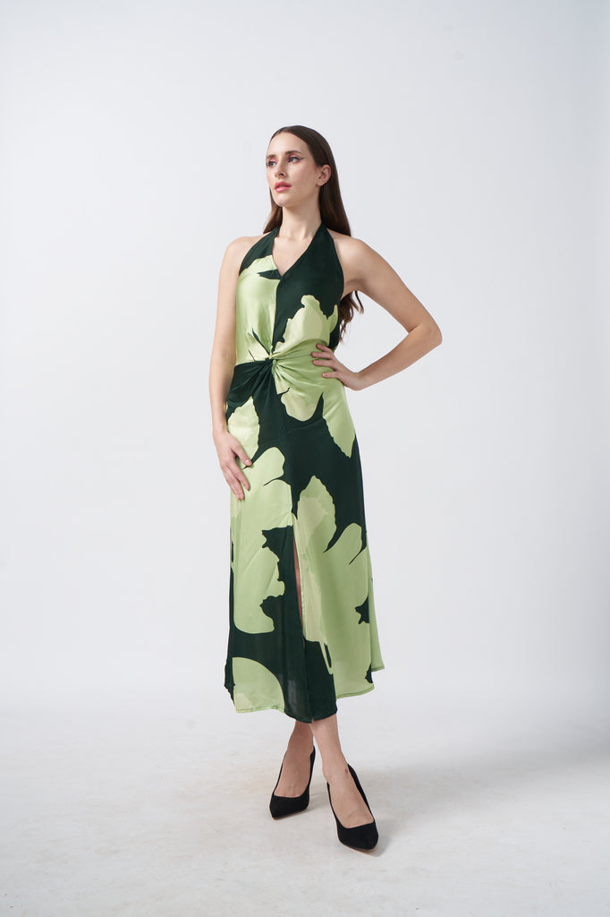 Model posing front-facing in a satin midi dress with green floral print and halter neck.