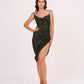 Model wearing a green floral printed muslin dress with asymmetric hem and ruched detailing, standing front-facing with one hand on waist.