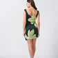 Rear view of the model in the green floral print satin dress, showing the back silhouette and strap design.