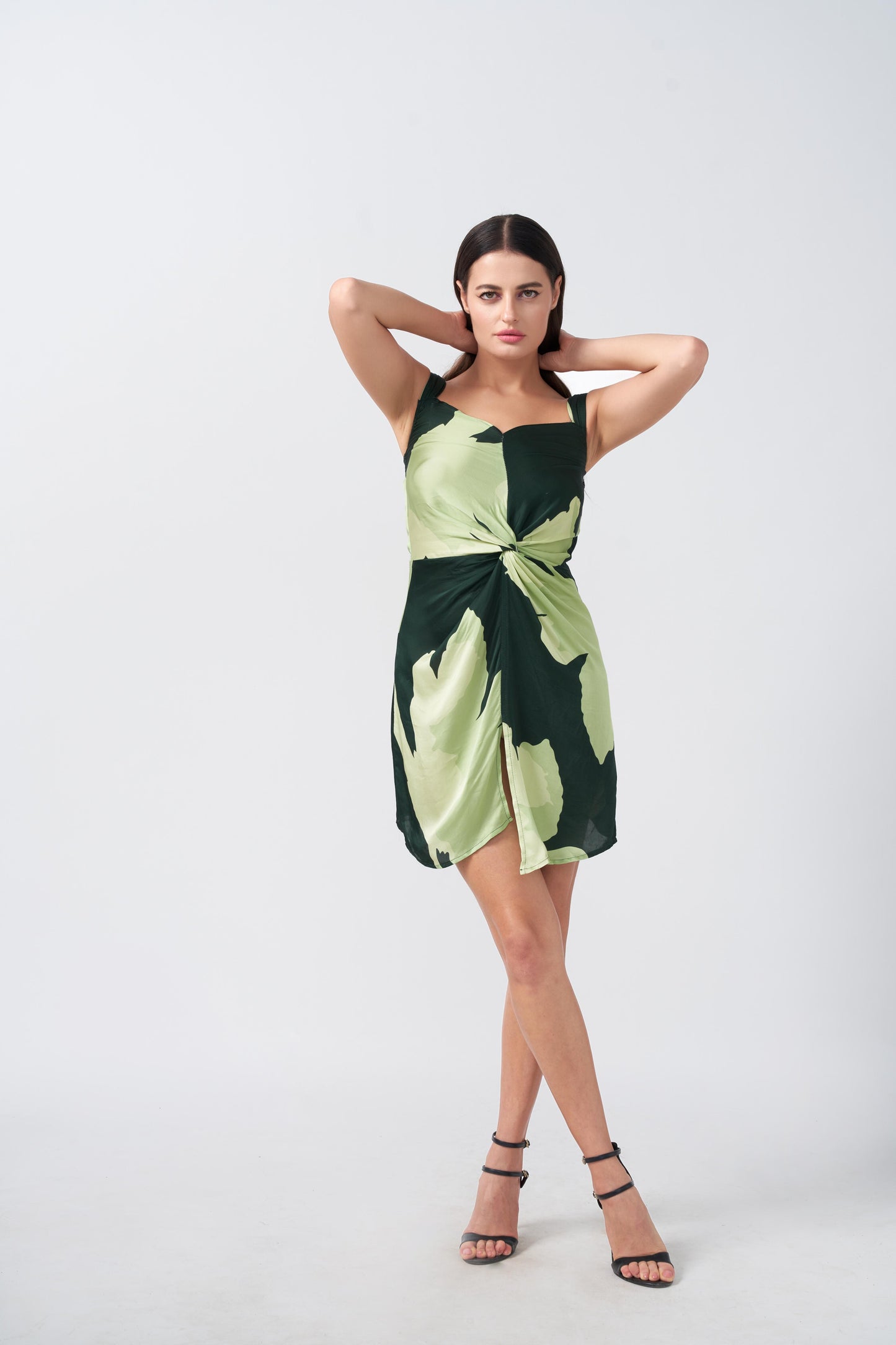 Model with arms up, highlighting the playful elegance and drape of the short green floral satin dress.