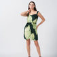 Model posing front-facing in a satin short dress with light and dark green floral print and twisted front knot.