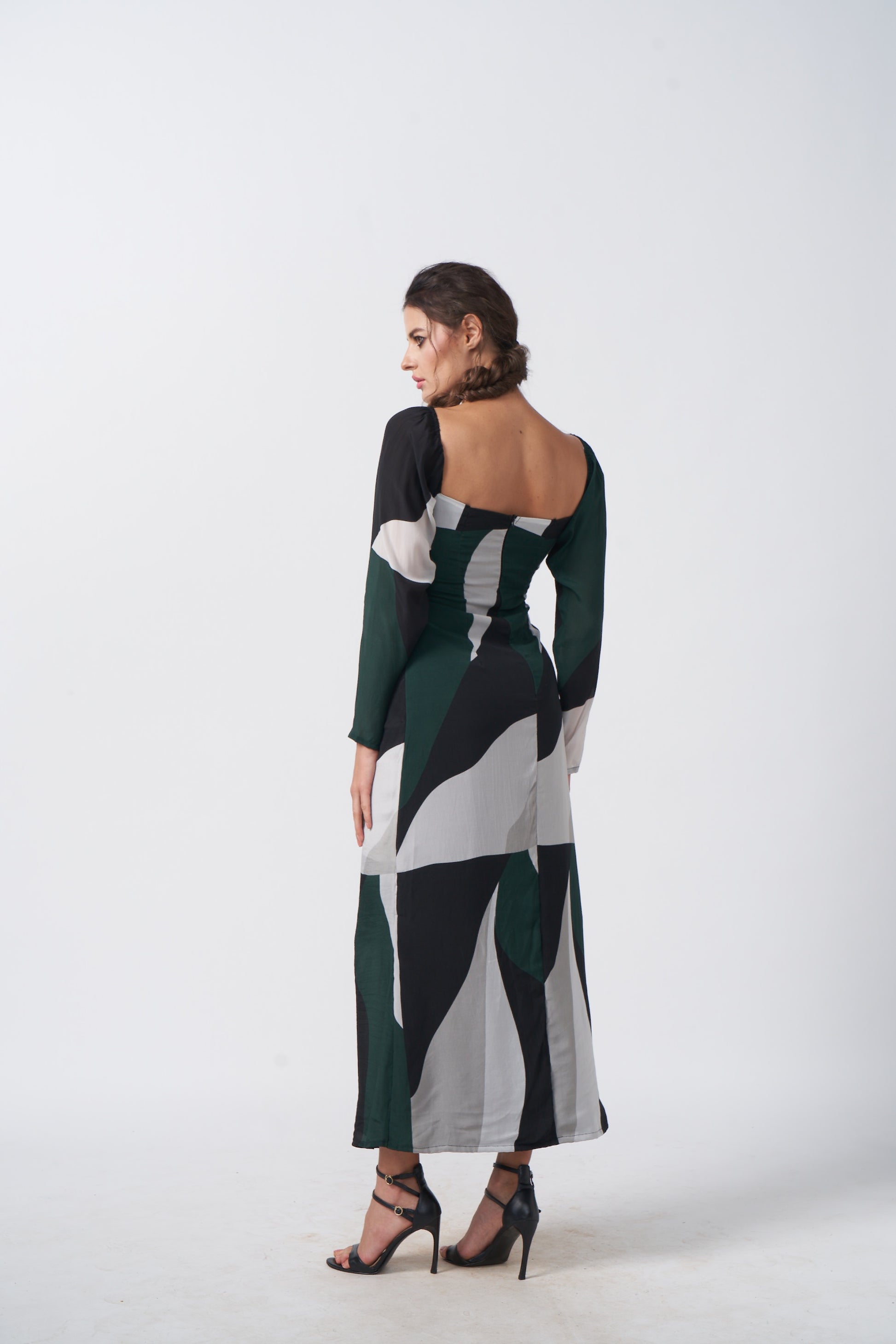 Back view of model wearing the crepe dress, showing the fall and structure of the long-sleeved silhouette.
