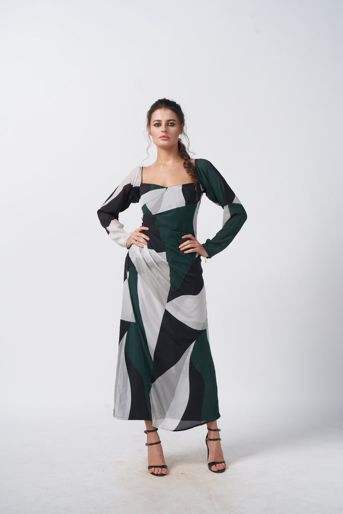 Model in front-facing pose wearing green, black, and grey abstract crepe dress with long sleeves.