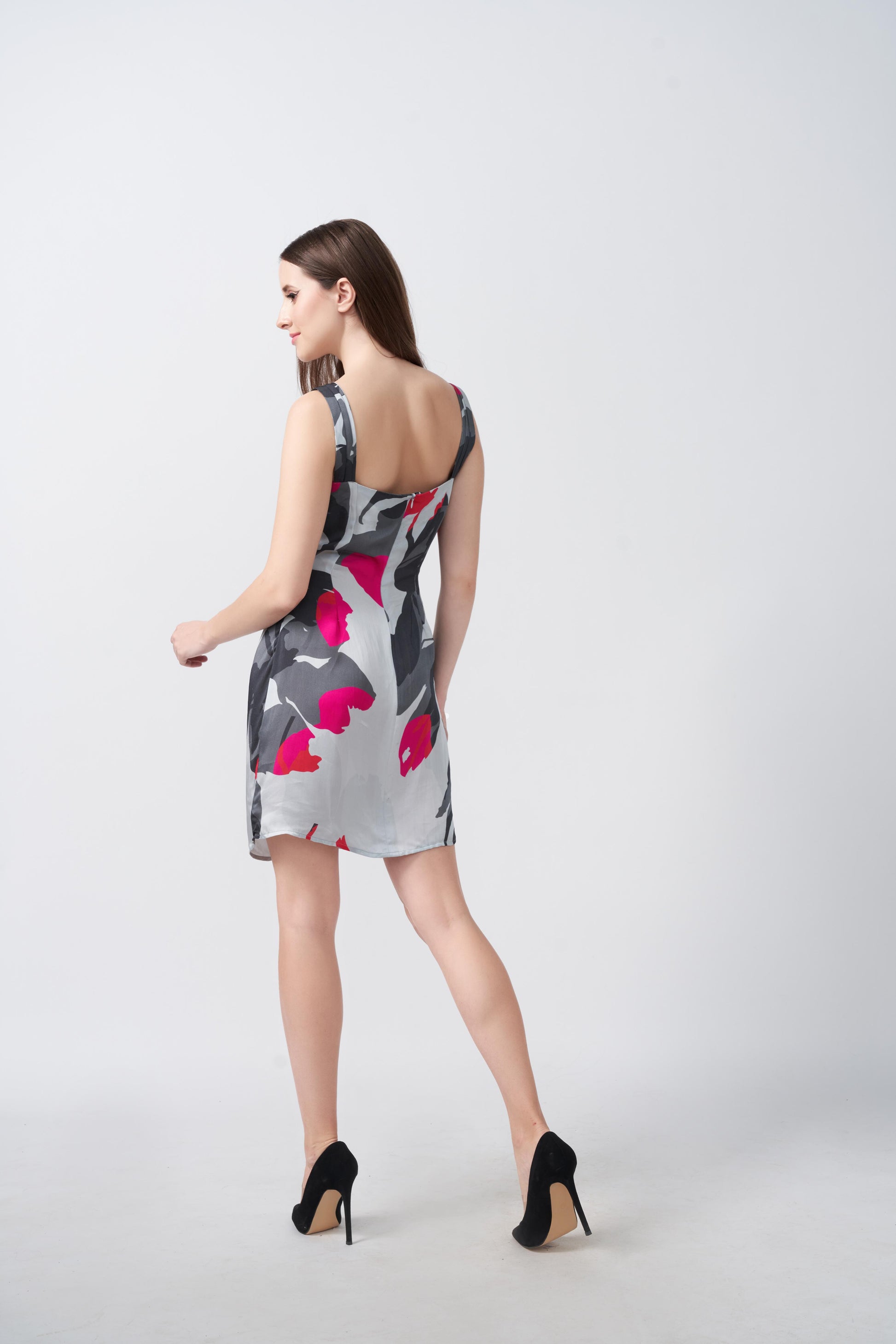 Back view of the model walking away in grey and white floral print dress, showing shoulder strap and hemline.