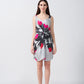 Model facing forward in a short grey satin dress with pink and white abstract floral print and front knot detail.