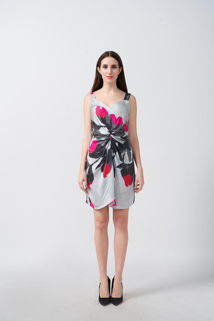 Model facing forward in a short grey satin dress with pink and white abstract floral print and front knot detail.