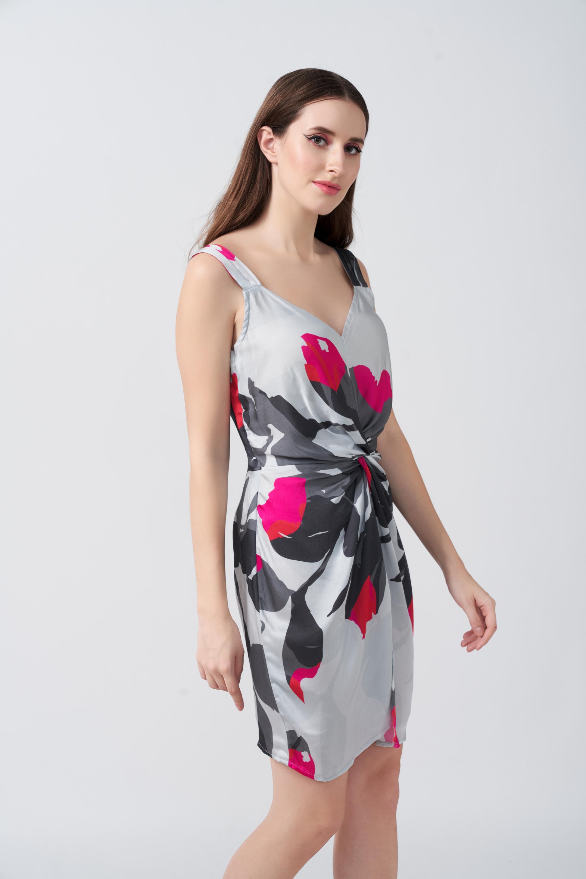 Side profile view of the model in grey abstract floral print short dress, emphasizing the drape and side cut.