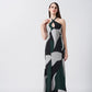 Model posing in full-length view of abstract printed dress featuring a halter tie-back neckline and flowy silhouette.