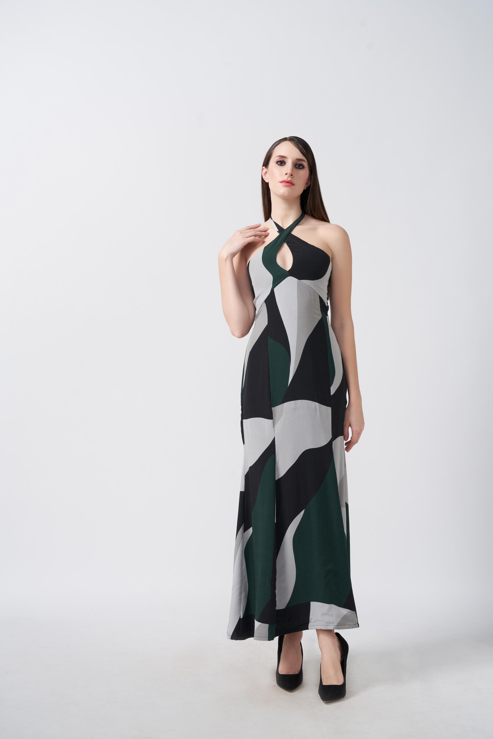 Model posing in full-length view of abstract printed dress featuring a halter tie-back neckline and flowy silhouette.