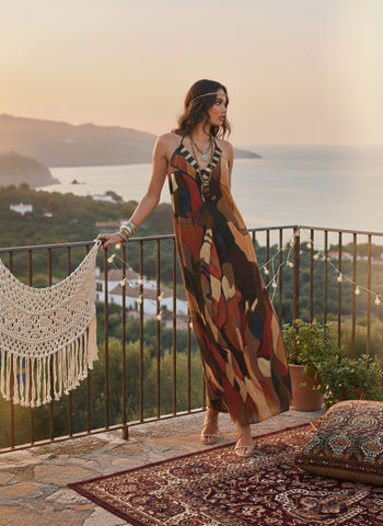 Sleeveless A-line maxi dress crafted from a lightweight Chinon blend, featuring an abstract print in deep red, warm ochre, olive green, and hints of navy.