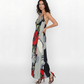 Backless halter-neck maxi dress with a bold, artistic floral print with oversized red roses and abstract gray and black patterns, paired with minimalist black strappy heels perfect for  summer evening events.