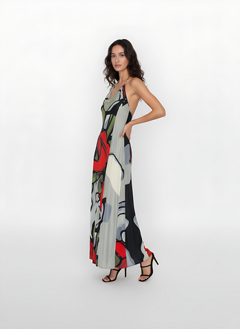 Backless halter-neck maxi dress with a bold, artistic floral print with oversized red roses and abstract gray and black patterns, paired with minimalist black strappy heels perfect for  summer evening events.