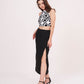 Model in a turned pose showing the halter neck design and clean silhouette of the high-slit black skirt.