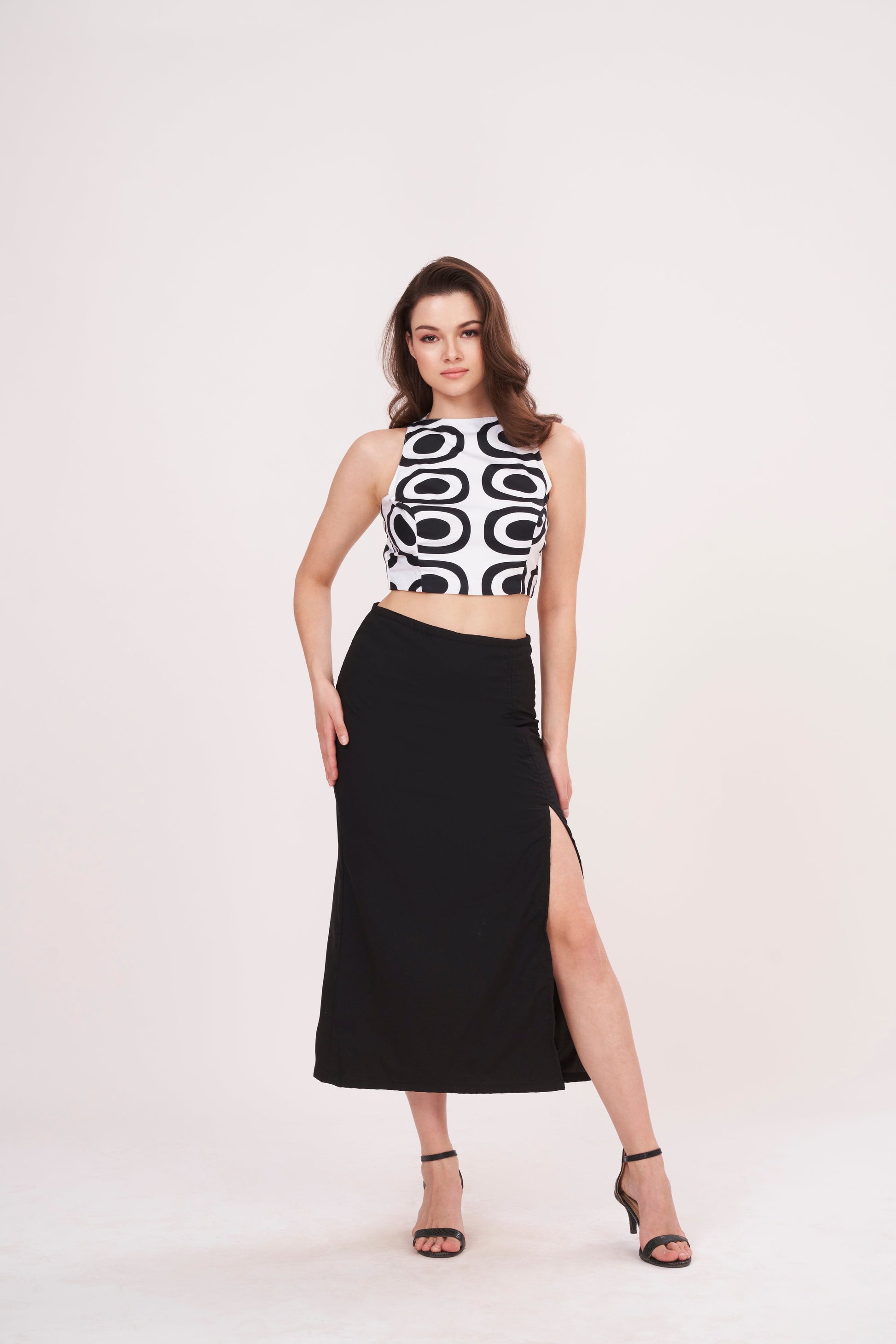 Square-shaped crop top with bold abstract print, paired with black thigh-high slit skirt for a striking ensemble