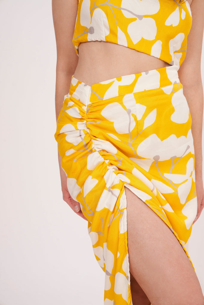 Stylish long skirt with vibrant yellow floral print, perfect for summer. Flattering waist cut creates stunning silhouette, while slit adds touch of elegance. 