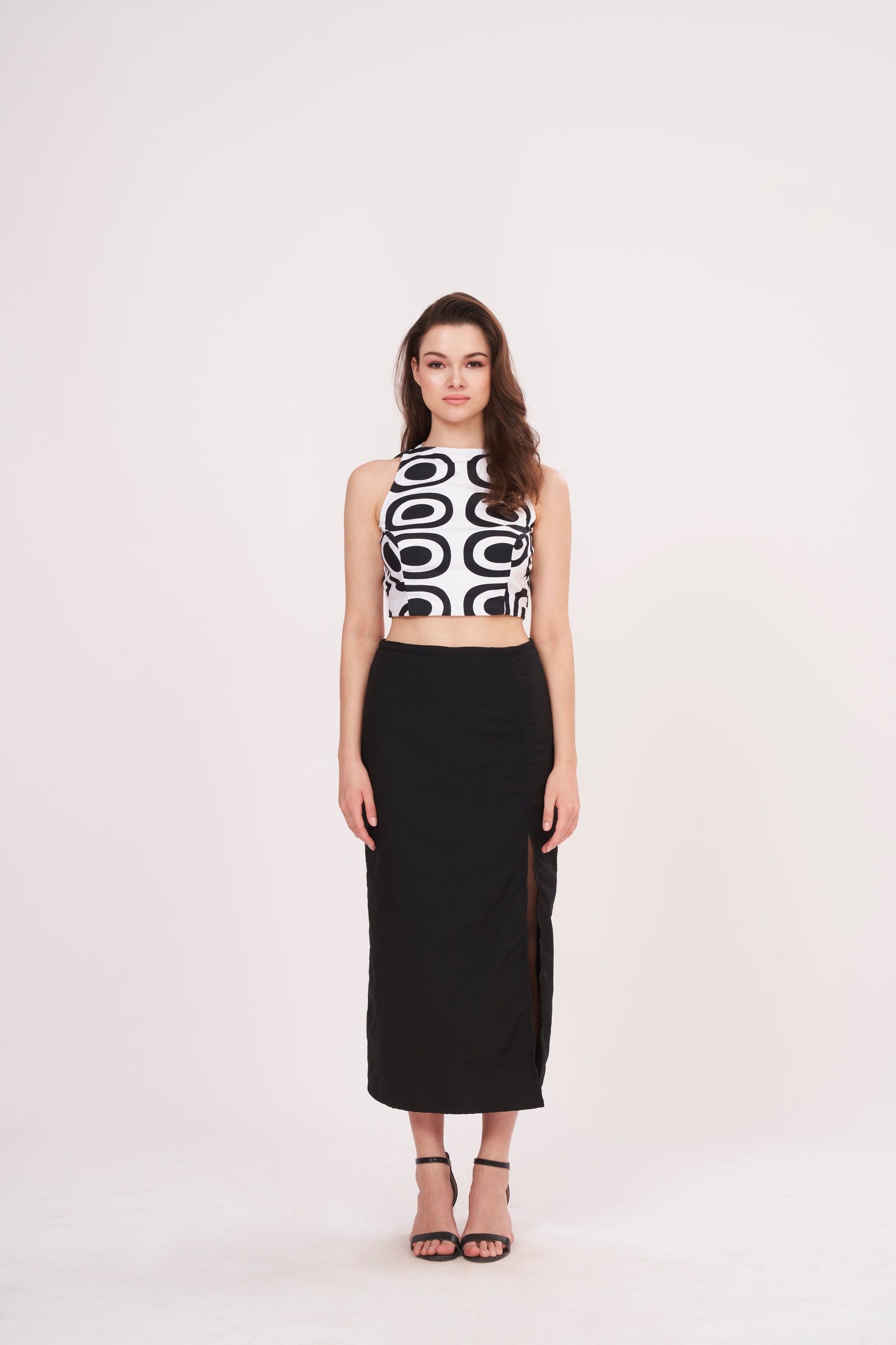 Square-shaped crop top with bold abstract print, paired with black thigh-high slit skirt for a striking ensemble