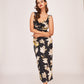 Model standing in a relaxed front-facing pose in the black satin floral dress, showcasing the elegant drape and twisted neckline.