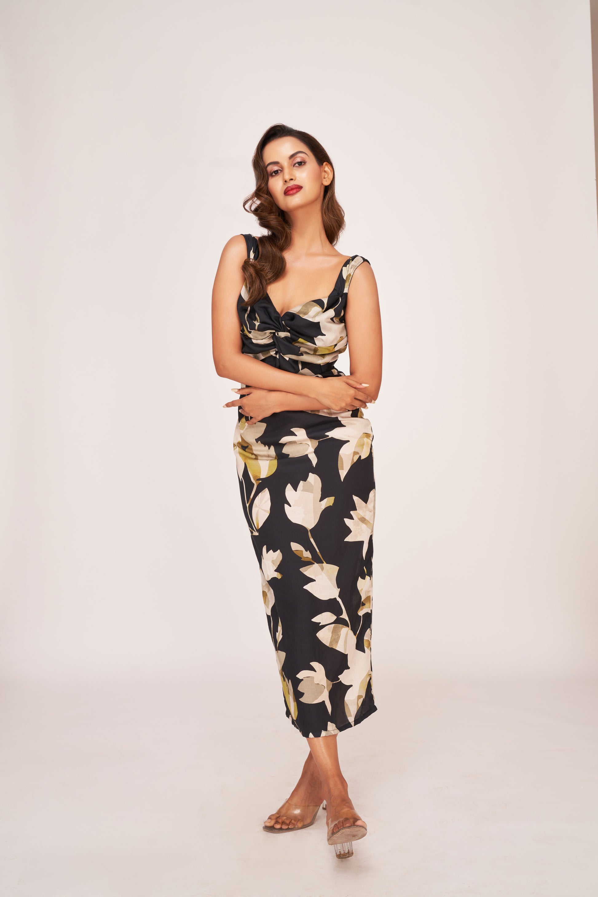 Model standing in a relaxed front-facing pose in the black satin floral dress, showcasing the elegant drape and twisted neckline.