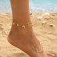 A charming imitation gold anklet with dainty dolphin and fish dangles, an ideal accessory for a relaxed day at the beach or a poolside brunch with friends.