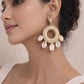 A woman wearing bohemian Shell Ring Drop Earrings featuring five cowrie shells dangling from a woven straw hoop with an imitation gold stud.