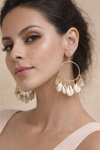 A woman modeling large imitation gold Shell Drop Earrings featuring a thin metallic hoop with multiple dangling white cowrie shells.