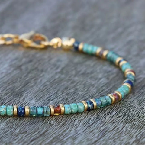 A vibrant, ethnic-style anklet featuring multi-toned natural stone seed beads in shades of turquoise, amber, and deep blue.
