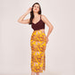 Model wearing a maroon bodice and abstract print satin midi dress, front-facing with hand resting on head.