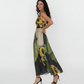 Full-length halter-neck dress with a sleeveless bodice. The design showcases a bold, artistic floral print with oversized yellow blossoms, sage green leaves, and charcoal abstract patterns.