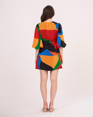Back of the mini dress displaying the vibrant geometric print continuity and relaxed puff sleeve fit.