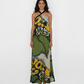 Ankle-length halter gown featuring a vibrant, oversized botanical print in moss green, golden yellow, and slate grey. The design flows into a graceful maxi-length skirt that makes it a perfect choice for sun-drenched garden weddings or elevated summer soirées.