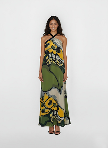 Ankle-length halter gown featuring a vibrant, oversized botanical print in moss green, golden yellow, and slate grey. The design flows into a graceful maxi-length skirt that makes it a perfect choice for sun-drenched garden weddings or elevated summer soirées.