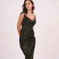 Side-facing pose of model in ruched floral midi dress with asymmetrical hem, showcasing fit and flare.