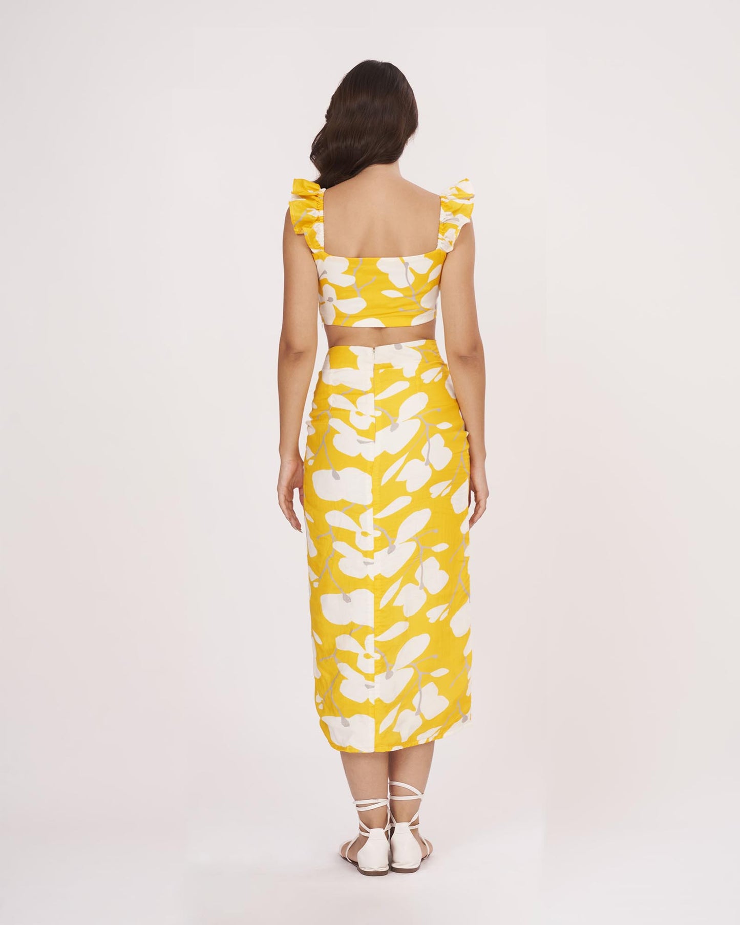 Rear view of the yellow printed co-ord set showing the ruched back detailing of the top and skirt with a full-length profile.