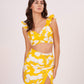 Model in yellow printed muslin co-ord set with sweetheart neckline, ruffle straps, and full view of abstract print skirt.