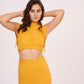 Model poses with hands behind her head, drawing attention to the clean lines of the sleeveless blouse and the confident styling of the look.