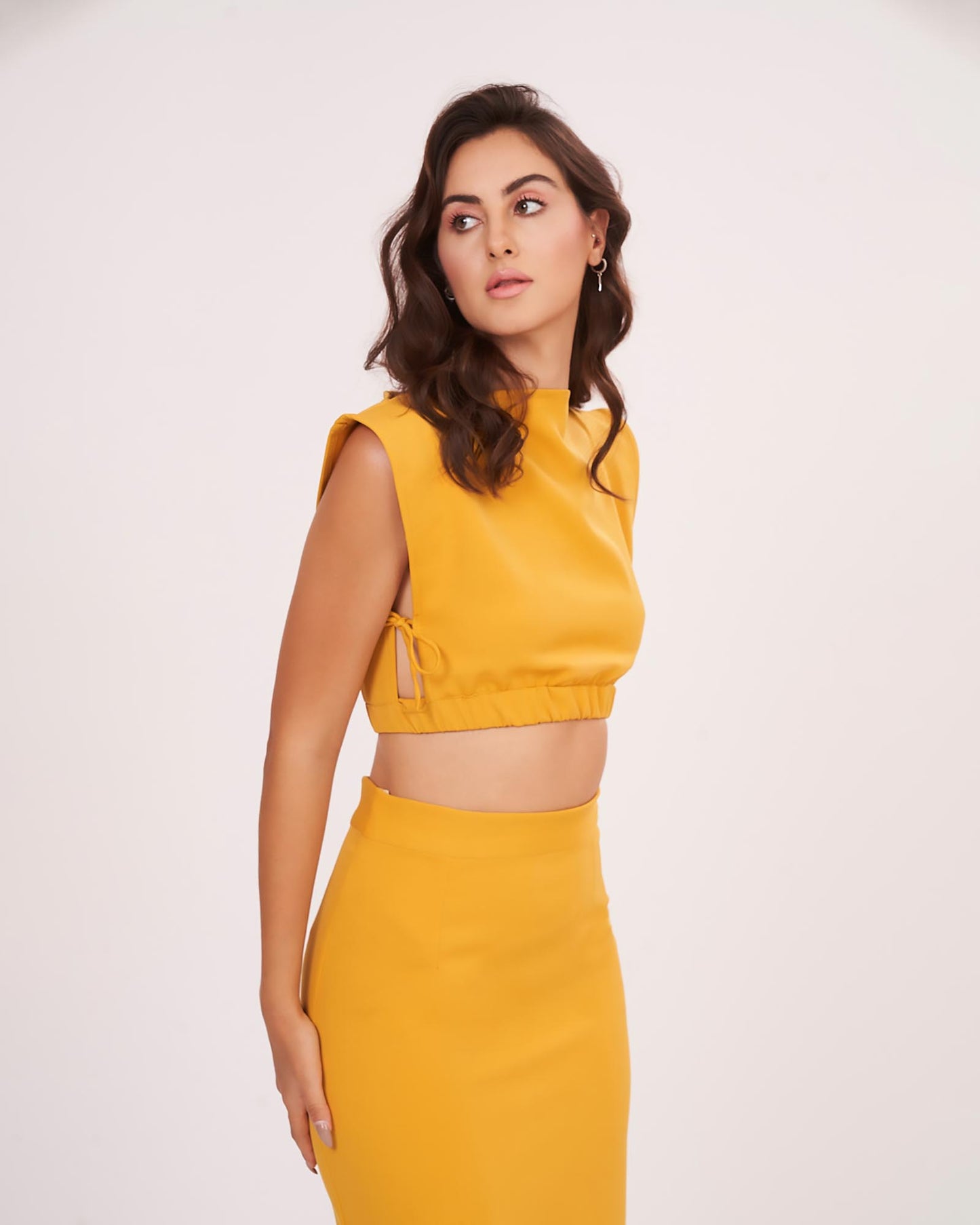 Close-up of the mustard yellow co-ord set showing the boat neckline and fitted bodice, emphasizing the sleek tailoring and structured form.