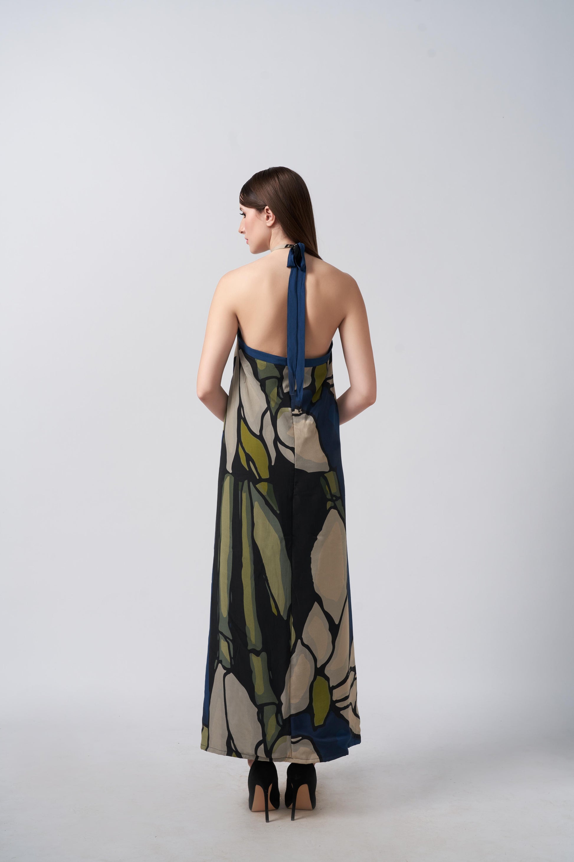 Back view of the model in navy blue and beige abstract floral halter dress, highlighting the tie-back detail and elegant drape.