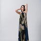 Model posing front-facing in navy blue and beige abstract floral halter neck dress, arms raised to showcase neckline.