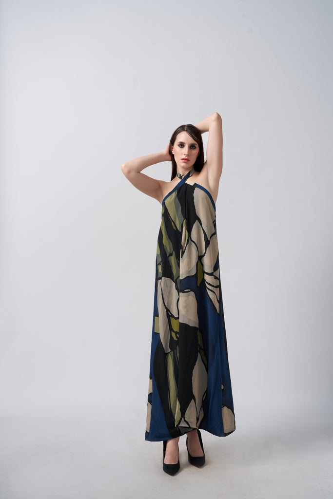 Model posing front-facing in navy blue and beige abstract floral halter neck dress, arms raised to showcase neckline.