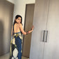 Model standing by wardrobe in navy and beige floral halter dress, offering a casual indoor styling view.