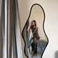 Model posing indoors in front of mirror in navy and beige floral dress, showing fashion-forward styling.