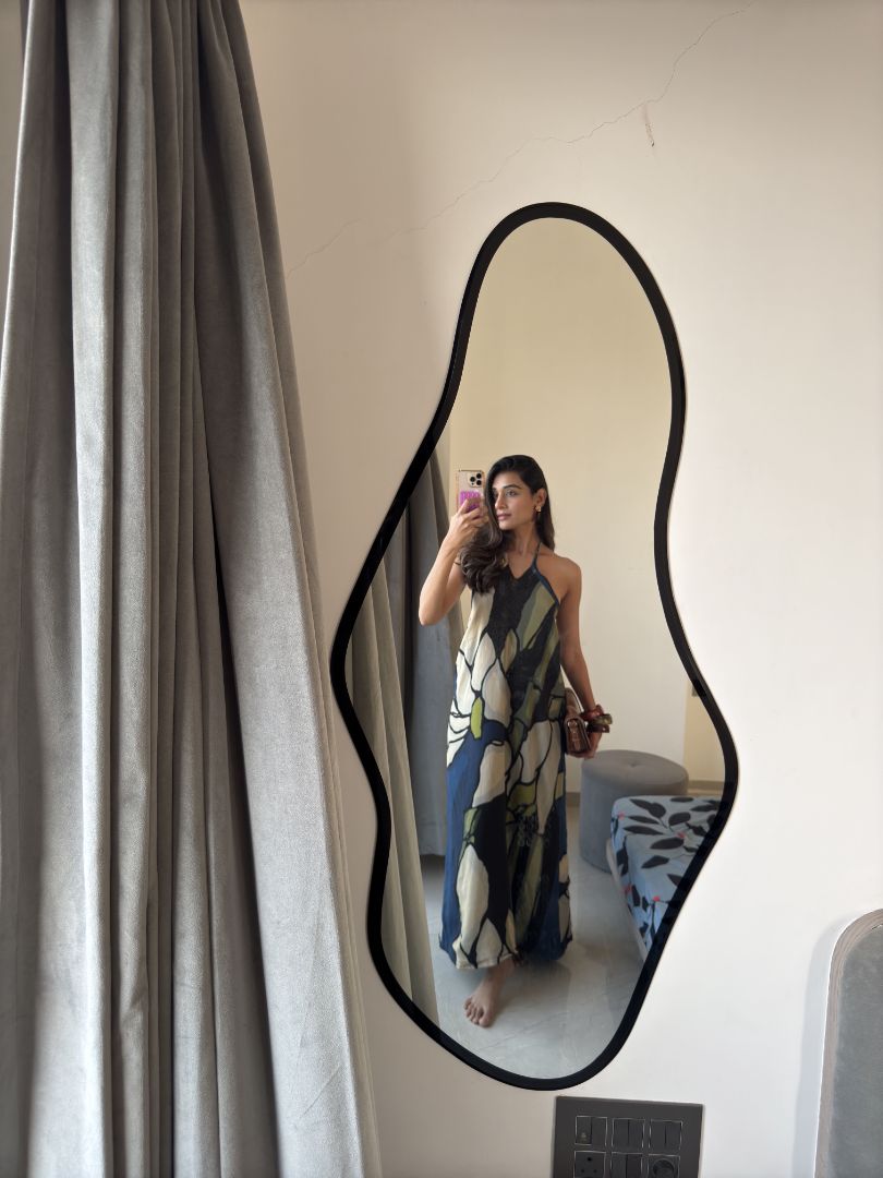 Model posing indoors in front of mirror in navy and beige floral dress, showing fashion-forward styling.