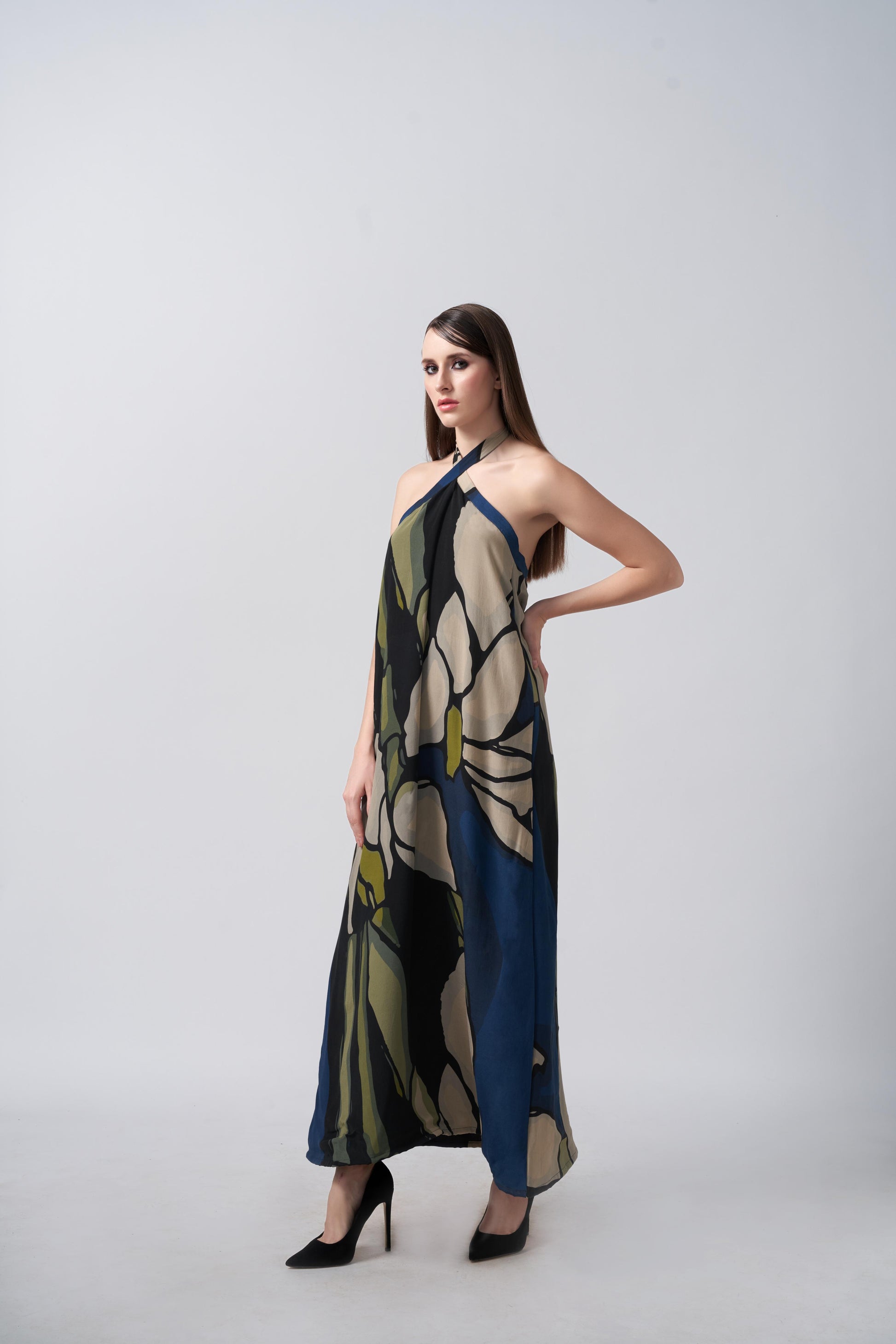 Model standing in studio setting in navy and beige floral halter dress, hands at sides for silhouette clarity.