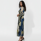 Long-sleeved column dress with a sleek, tailored side profile  that creates a flattering drape. The fabric is a smooth, lightweight material printed with large-scale geometric shapes in floral tones.