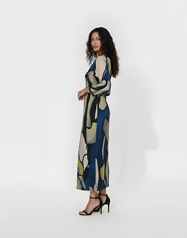 Long-sleeved column dress with a sleek, tailored side profile  that creates a flattering drape. The fabric is a smooth, lightweight material printed with large-scale geometric shapes in floral tones.
