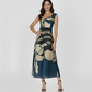 Full-length, one-shoulder dress featuring a striking oversized floral print in shades of midnight blue, sage green, and muted cream. The sleek, asymmetrical one-shoulder neckline creates a modern silhouette.