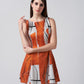 Close-up of model wearing a sleeveless burnt orange cotton satin dress with abstract print and structured neckline.